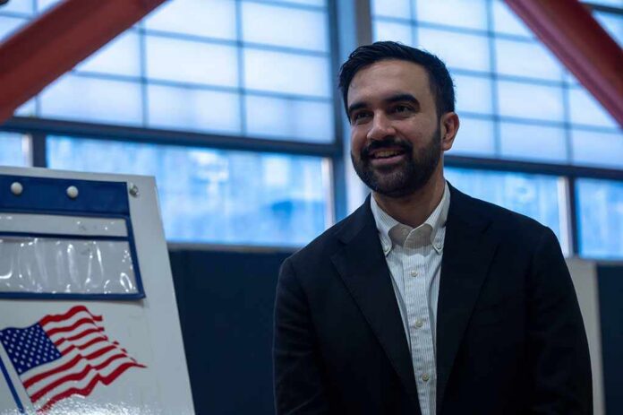 Democratic,New,York,City,Mayoral,Candidate,Zohran,Mamdani,And,His Zohran Mamdani smiling indoors near a voting sign with an American flag
