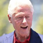 Millions Flow Into A Closely Watched State Race Bill Clinton smiling outdoors in a blue blazer and red shirt