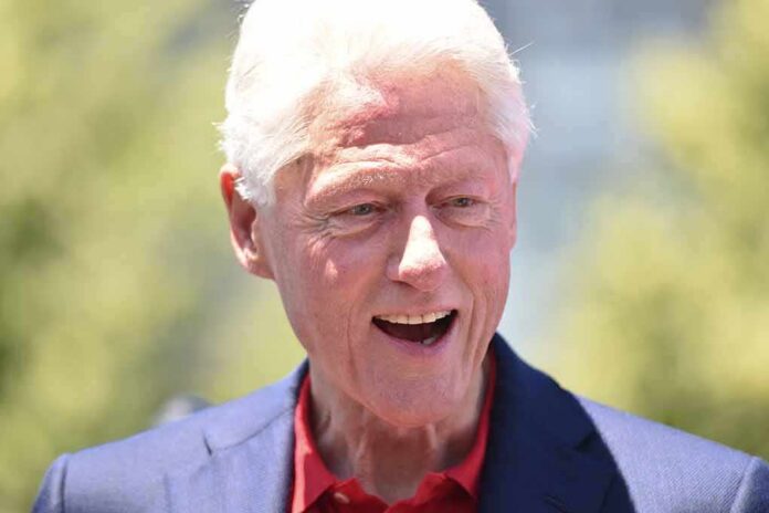 Bill Clinton smiling outdoors in a blue blazer and red shirt