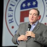 Mike Huckabee speaking on stage with a microphone