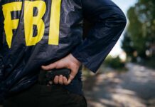 FBI agent in jacket drawing a handgun