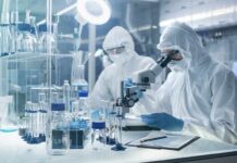 Lab Plague Death Triggers U.S. Alarm Scientists in protective suits using a microscope in a laboratory