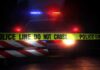 Police car behind crime scene tape at night