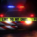 A Night Of Costumes Ends In Gunfire Police car behind crime scene tape at night