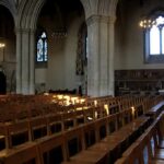 Sanctuary Shock: Giant Cross Comes Down Rows of wooden chairs inside a Gothic church nave