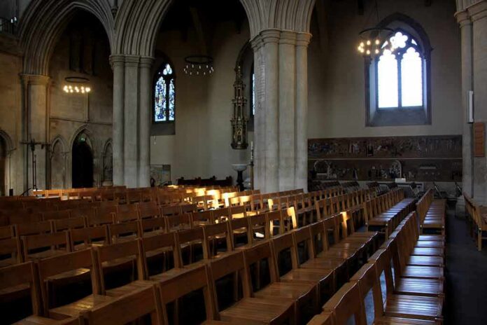shutterstock_716340232 Rows of wooden chairs inside a Gothic church nave