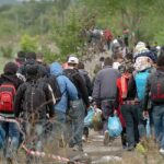 Group of people walking along a rural path carrying bags