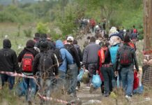 EU Money Trails – What’s Really Moving Migrants? Group of people walking along a rural path carrying bags